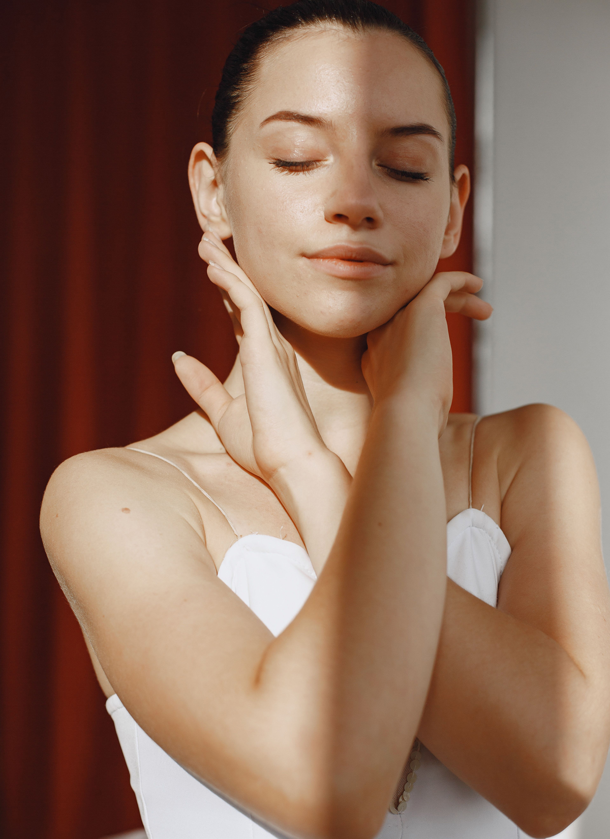 Woman gently touching her neck and jawline, representing natural results of a Beverly Hills facelift